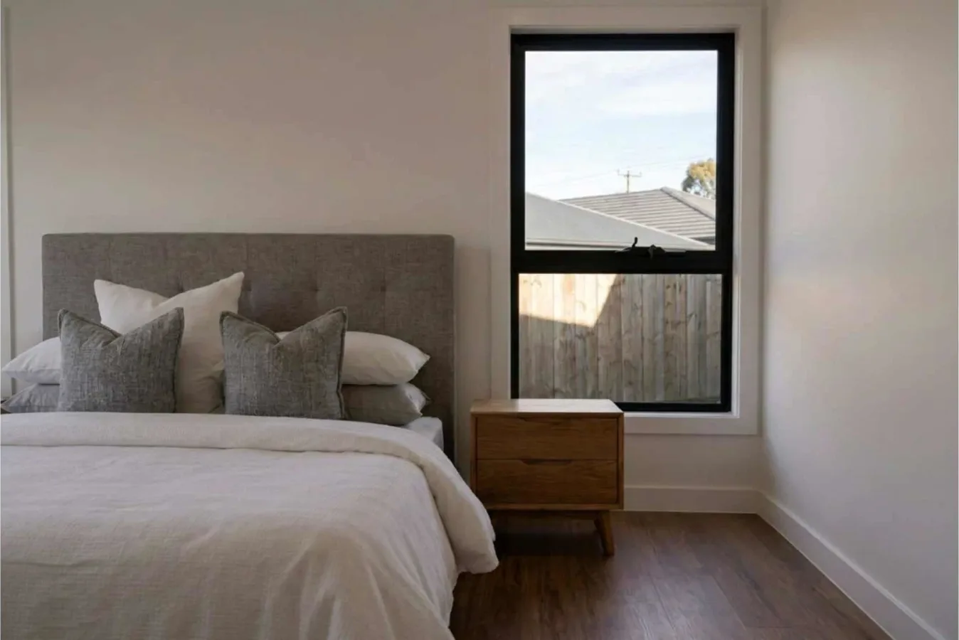 Bedroom with an upholstered bedhead and a window beside the bed