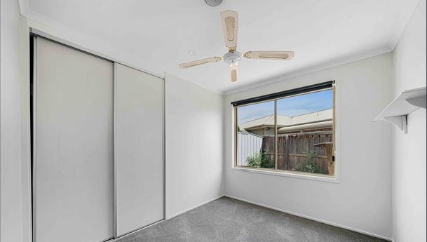 Carpeted bedroom with built-in wardrobe and ceiling fan