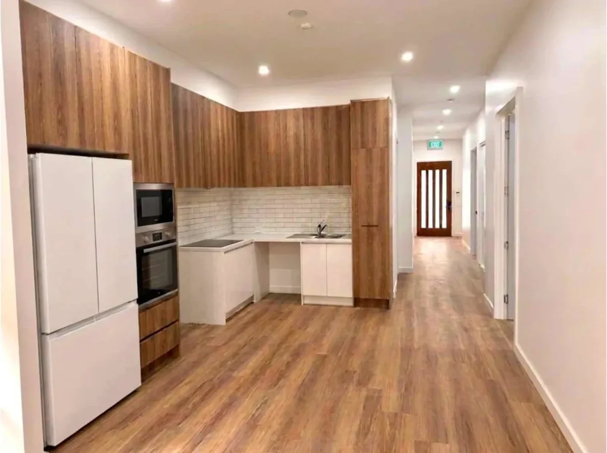 Kitchen with timber cabinetry, a wall oven and a wide walkway through to the hall