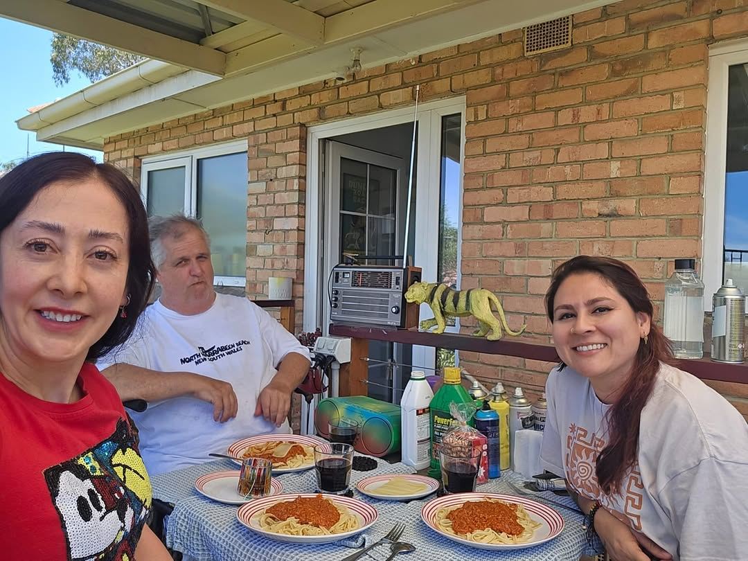 Participants and support workers sharing a meal outdoors