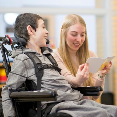 A young man in a wheelchair reading a book