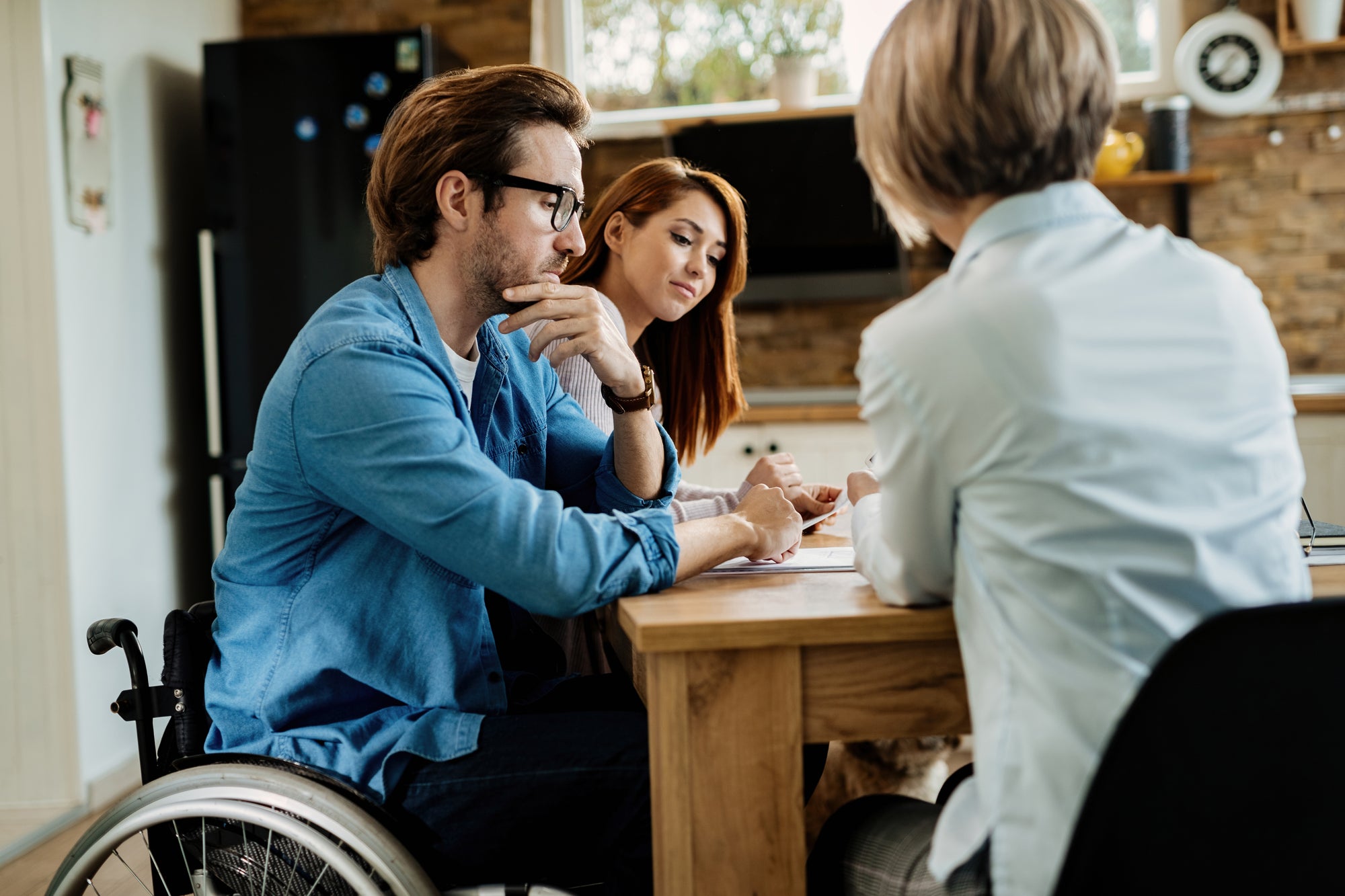 A coordinator meeting with a couple across a table to discuss supports