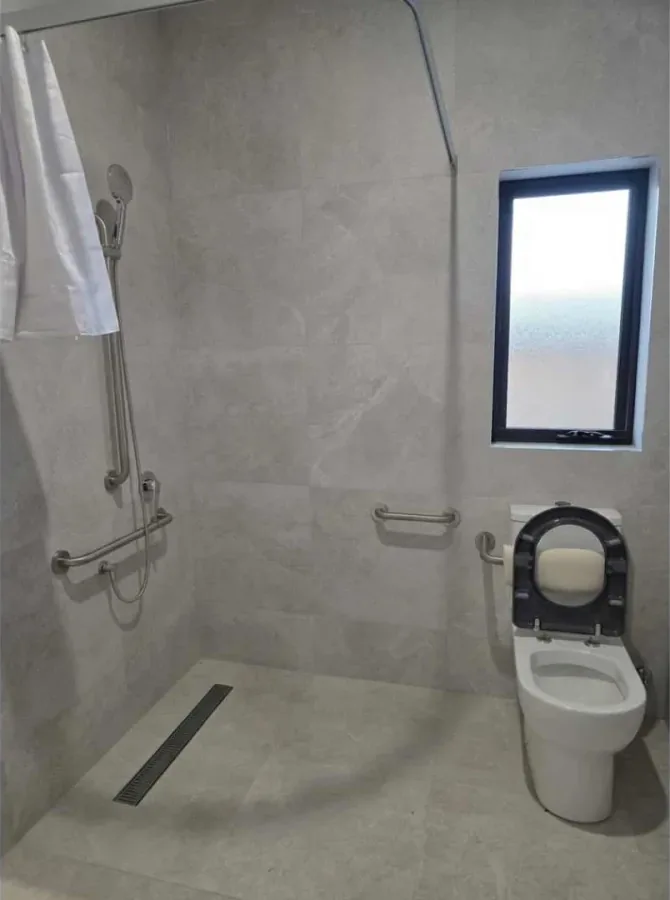 Accessible bathroom with a level-access shower, grab rail and fold-down seat