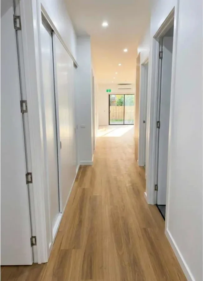 Wide hallway with level flooring and clear turning space between rooms